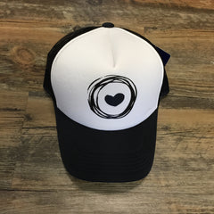 Black and white trucker cap with Corazon de Vida logo