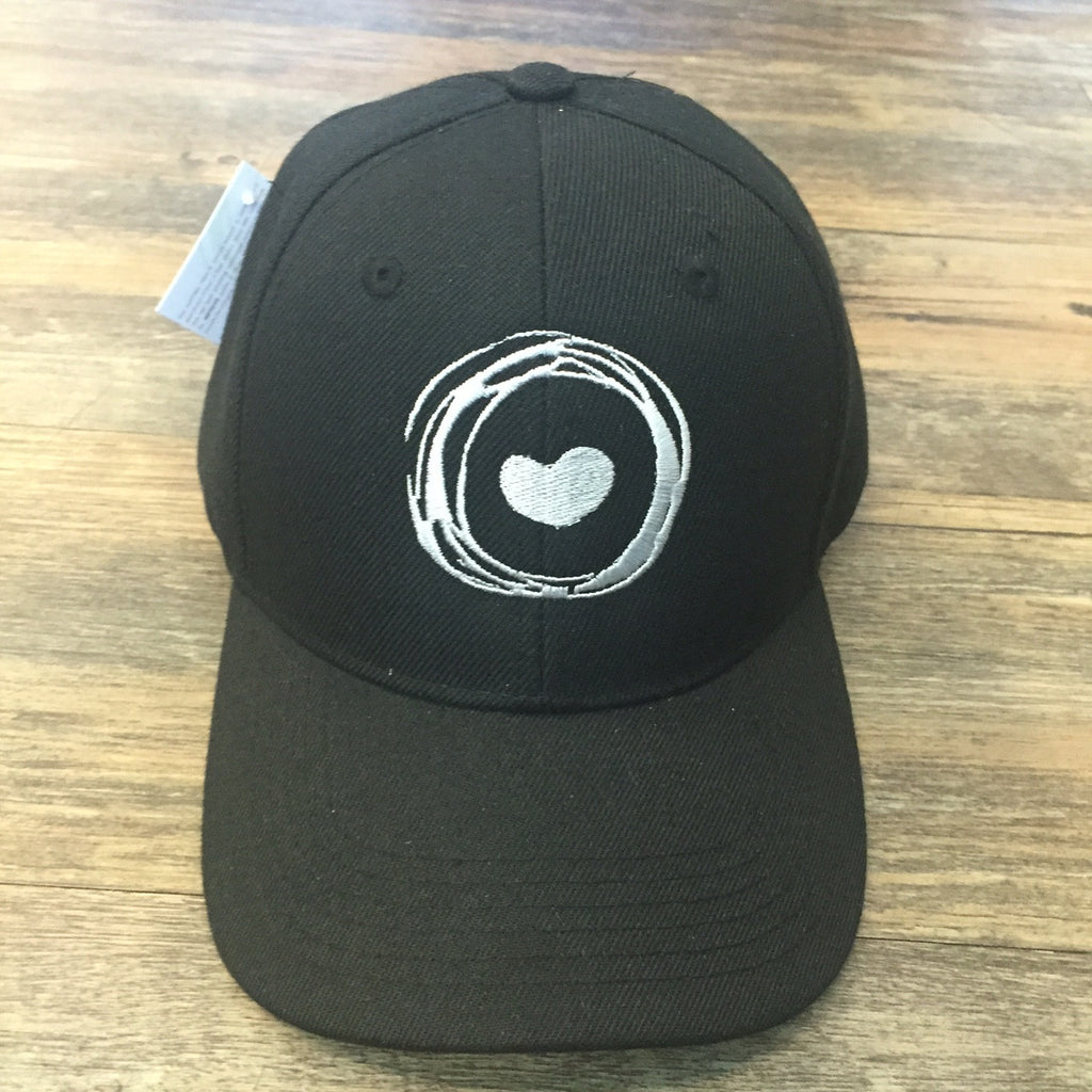 Front of black hat embroidered with Corazon de Vida logo 